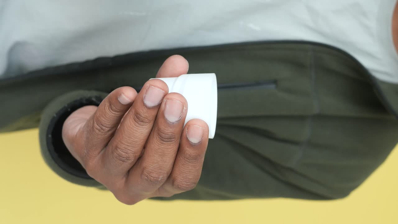 한 사람 이 컵 에 구강 용액 을 부어 놓고 있다