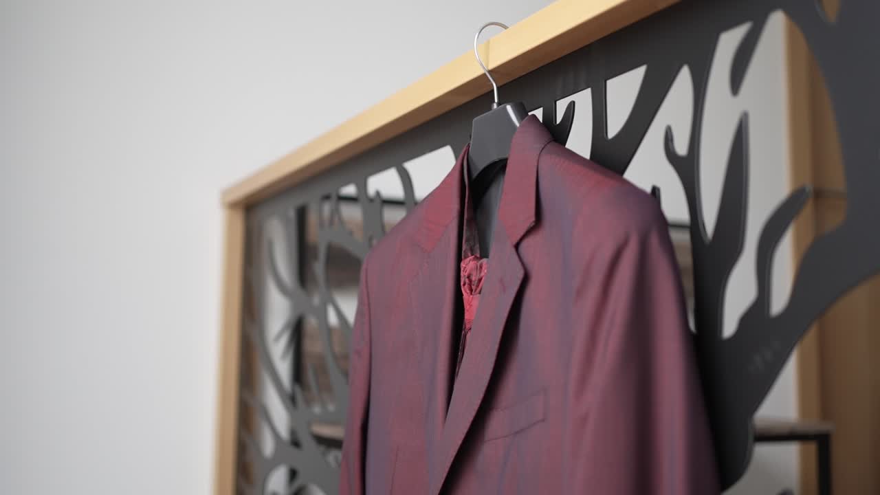 화려한 빨간색 웨딩 슈트가 실내에서 장식적인 현대적인 배경에 걸려 있습니다.