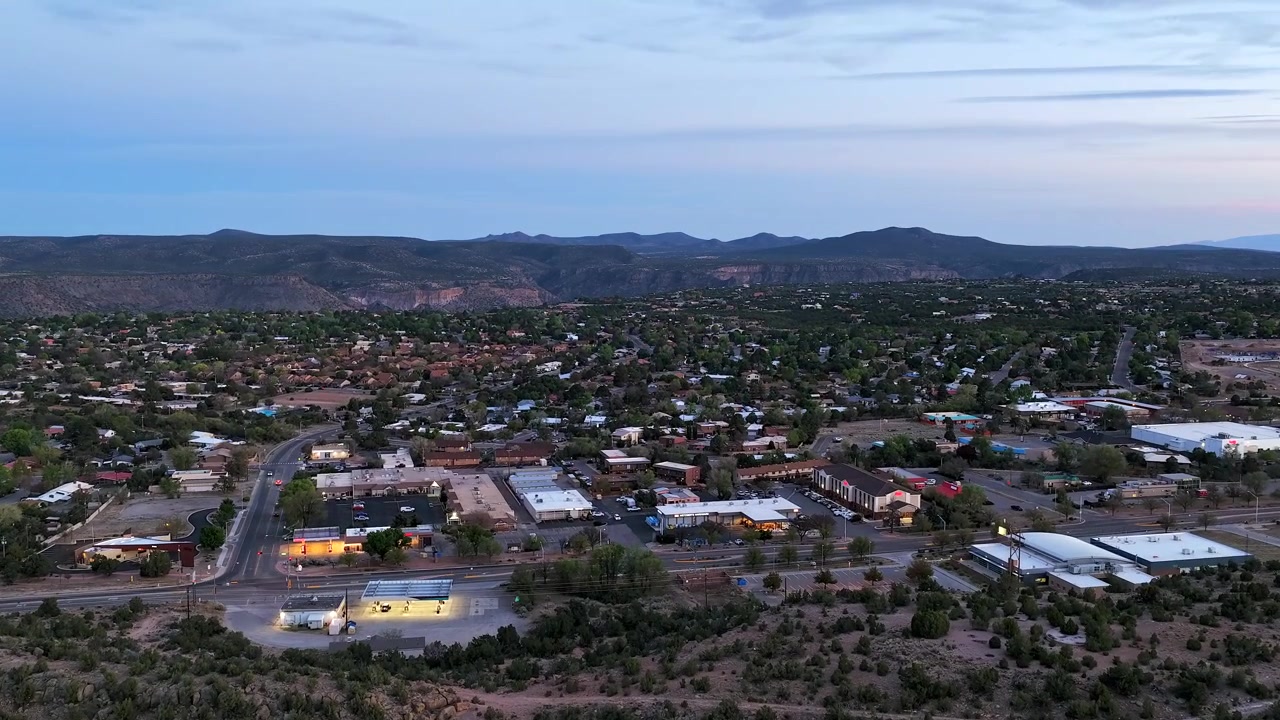 Timelapse 4K con drone cattura un volo aereo verso una cittadina suburbana situata su un altopiano di canyon. Il movimento cinematografico rivela strade residenziali e case sotto un cielo crepuscolare rosa e blu tenue