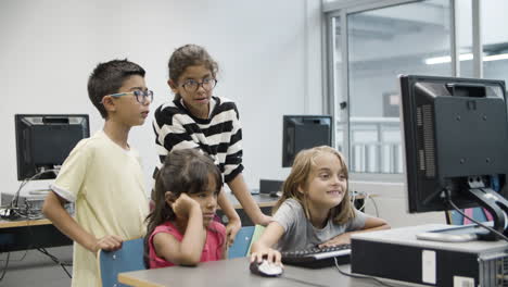 Multiethnic-children-looking-at-computer-monitor-during-computer-science-lesson