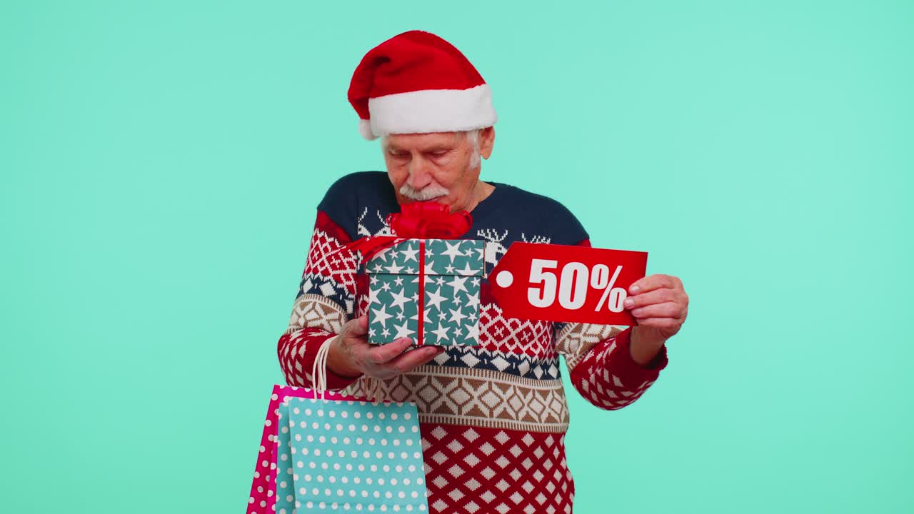 hombre anciano en suéter de navidad mostrando caja de regalos y 50 por ciento de descuento inscripciones texto de pancarta