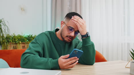 sad indian man use smartphone surprised by bad news fortune loss fail lottery results deadline