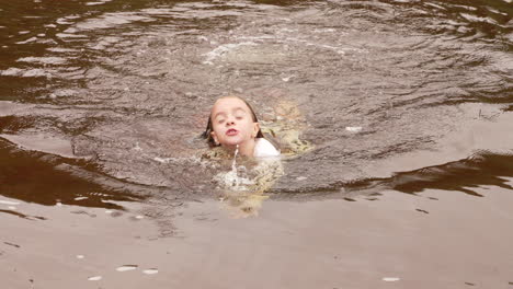 a happy little girl swimming in a lake during a summer vacation, slow motion