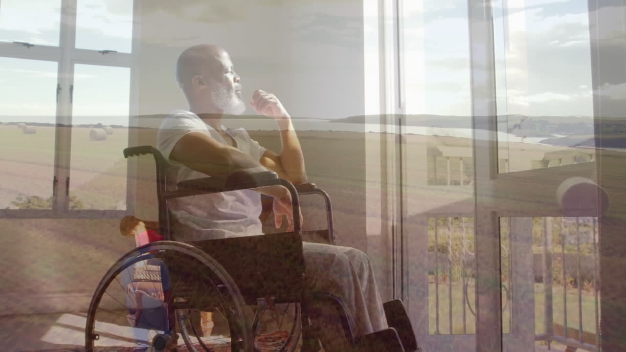 Man in wheelchair thoughtfully gazing outside, watching animation on laptop screen