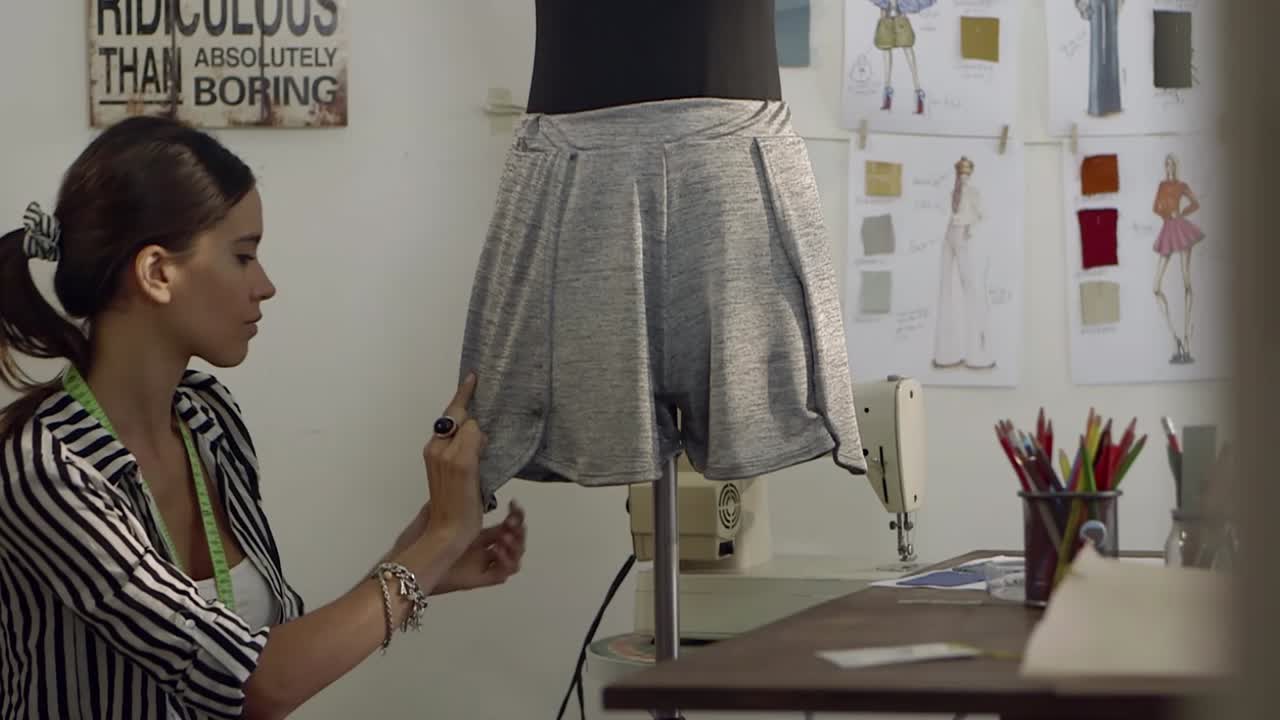 Jovem estilista de moda ajustando roupa em manequim no estúdio