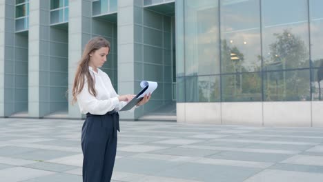 Young-woman-with-clipboard-inspecting-modern-office-building