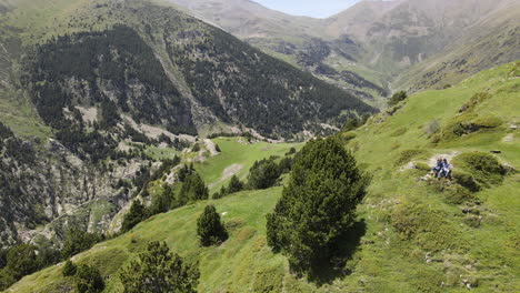 Luftaufnahme-Einer-Rückwärts-Fliegenden-Drohne,-Die-Ein-Paar-Zeigt,-Das-Sich-Ausruht,-Während-Es-Die-Beeindruckende-Bergkulisse-Der-Pyrenäen-Genießt