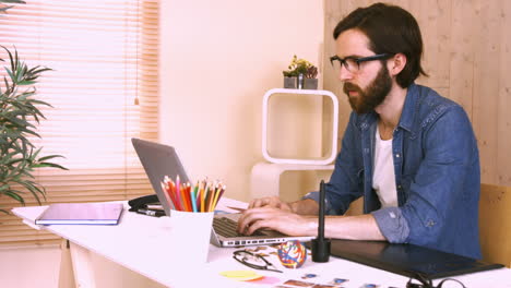 trabajador casual en su escritorio usando una computadora portátil