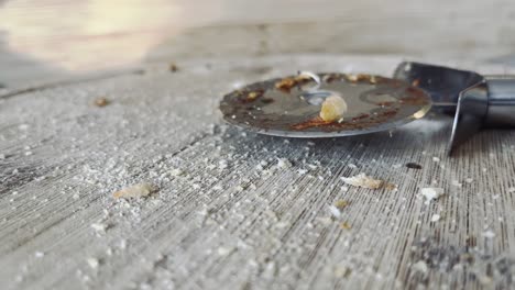 a used pizza cutter is placed on a wooden board and picked up again