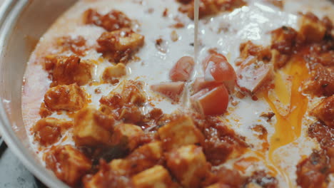 close-up of cooking paneer butter masala with cream and tomatoes