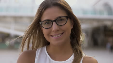 hermosa chica con gafas sonriendo a la cámara en la calle