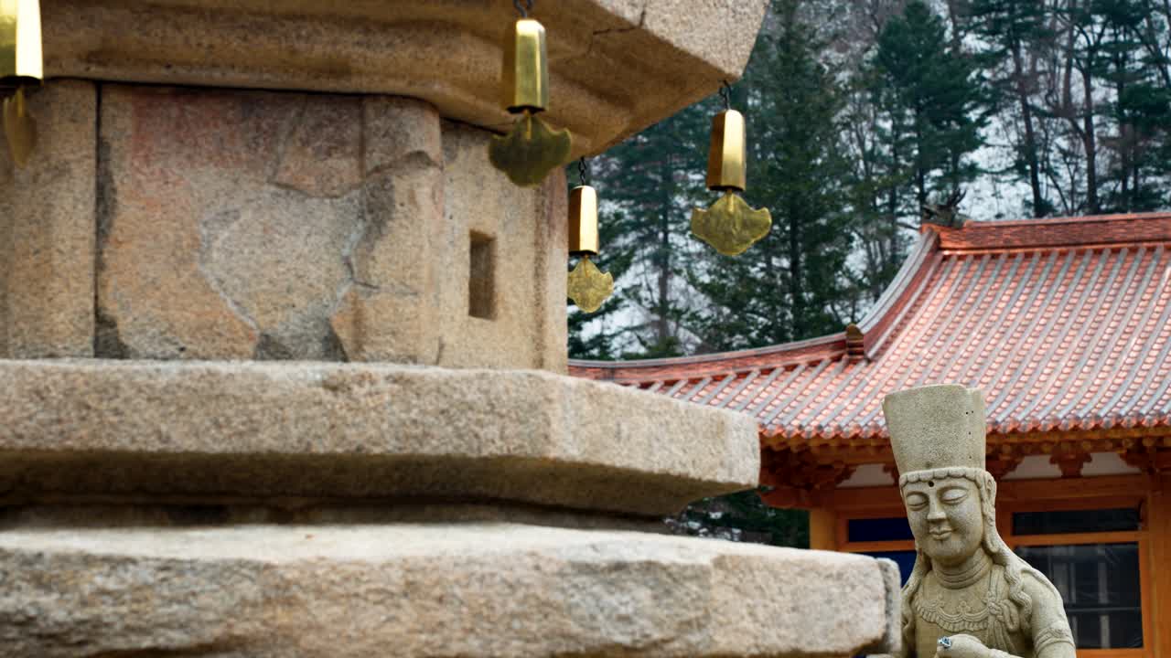 Close-up of an ancient stone pagoda with golden wind chimes and a Buddhist statue at Sangwonsa Temple in Pyeongchang South Korea
