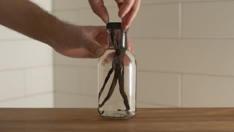 male hands screwing lid on top of vanilla bottle before the fermentation process has taken place