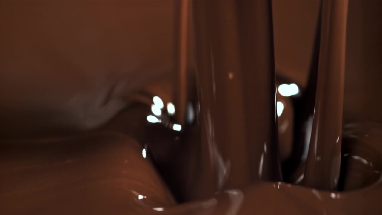 Primer plano a cámara lenta de chocolate derretido vertiéndose y goteando