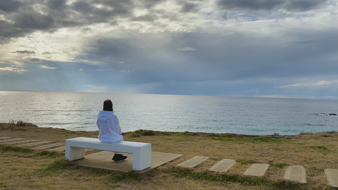 키프로스 파포스에 있는 벤치에 혼자 앉아 있는 어린 소녀