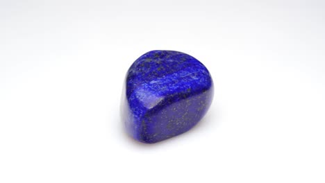 piedra preciosa natural de lapis lazuli en el fondo blanco en la mesa de giro