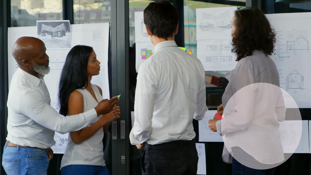 Diverse Business Team Collaborating on Architectural Plans in Modern Office