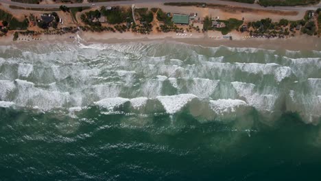Waves-rolling-towards-the-shore-revealed-by-the-drone-hovering-above-this-picturesque-beachfront-in-Porlamar,-Margarita-Island,-Venezuela