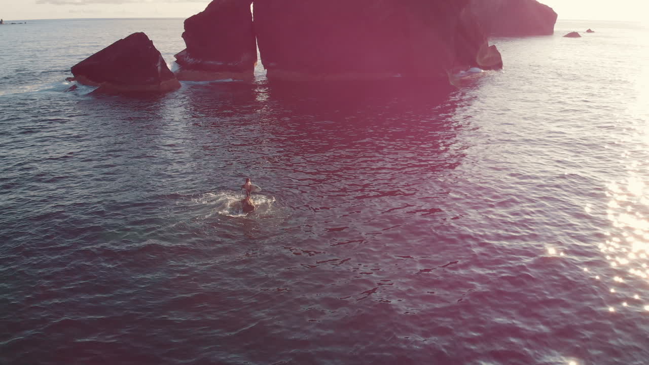 Person standing on a rock in the ocean at sunrise
