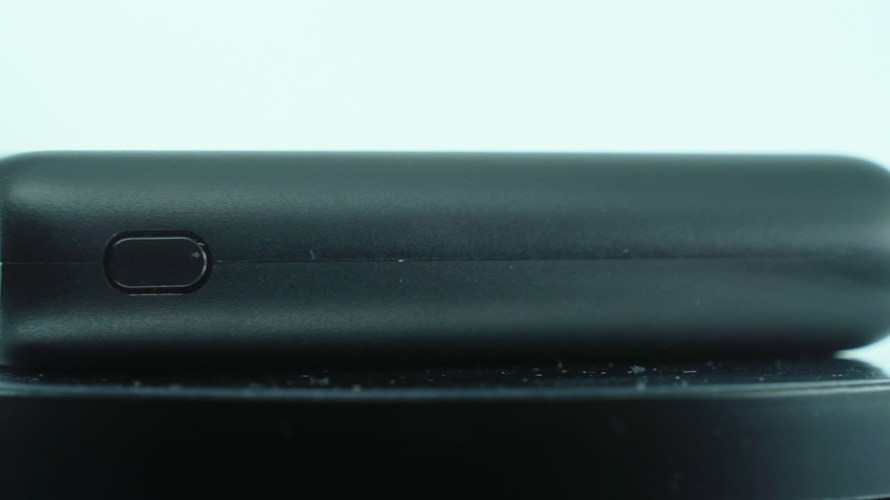 un primer plano de un banco de energía negro en un soporte giratorio 360, cámara lenta, iluminación de estudio, video 4k