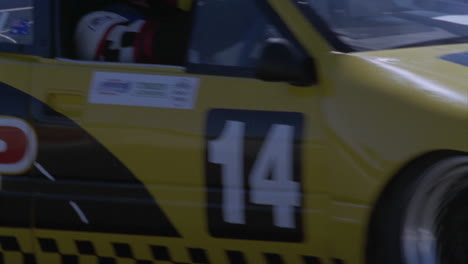 a yellow racing car drives around a race track