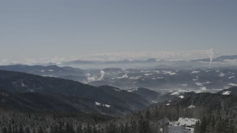 kope winter resort rv and car parking lot in the pohorje mountains with smoke in the distance, aerial tilt up reveal shot