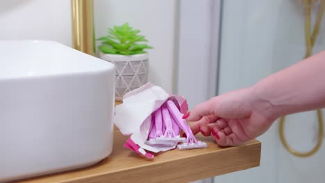 dama con uñas rojas tomando afeitadora de una bolsa de plástico abierta en un nuevo baño elegante