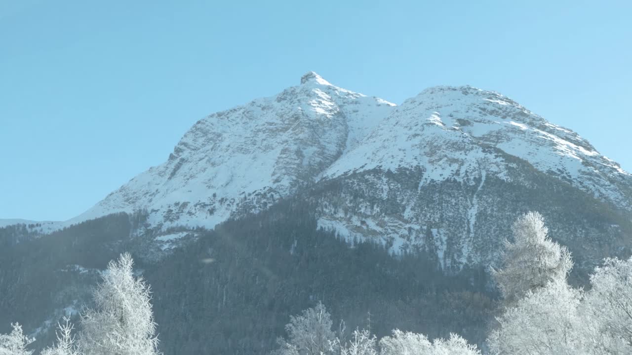 vista de camión de picos montañosos cubiertos de nieve, árboles y niebla en una mañana soleada en suiza