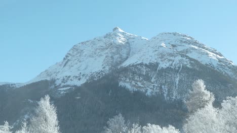 car view of snow covered mountain peaks, trees and fog on a sunny morning in switzerland