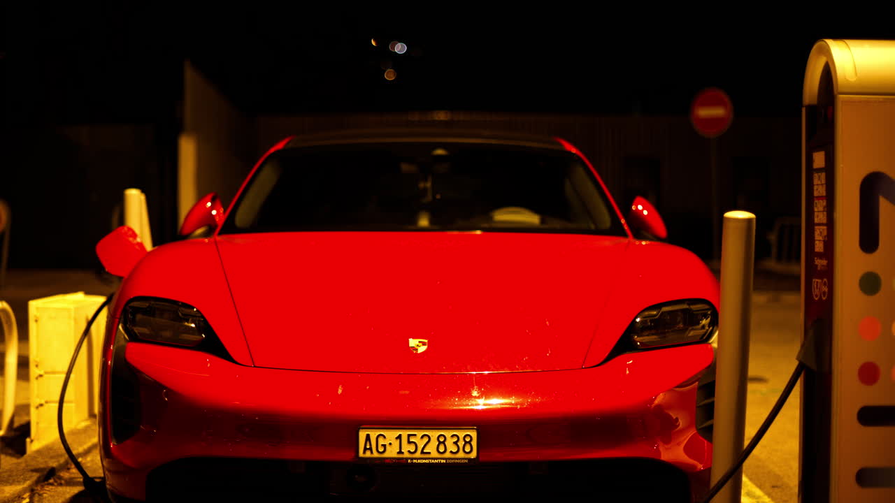 Aargau, Switzerland - September 14, 2024: Red Porsche Taycan charging on the street at night