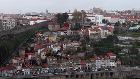 old colorful buildings of porto next to muralha fernandina and dos guindais cable car