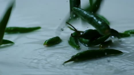 Pimientos-Verdes-Enteros-Caen-Al-Agua-Sobre-Fondo-Blanco-En-Cámara-Lenta