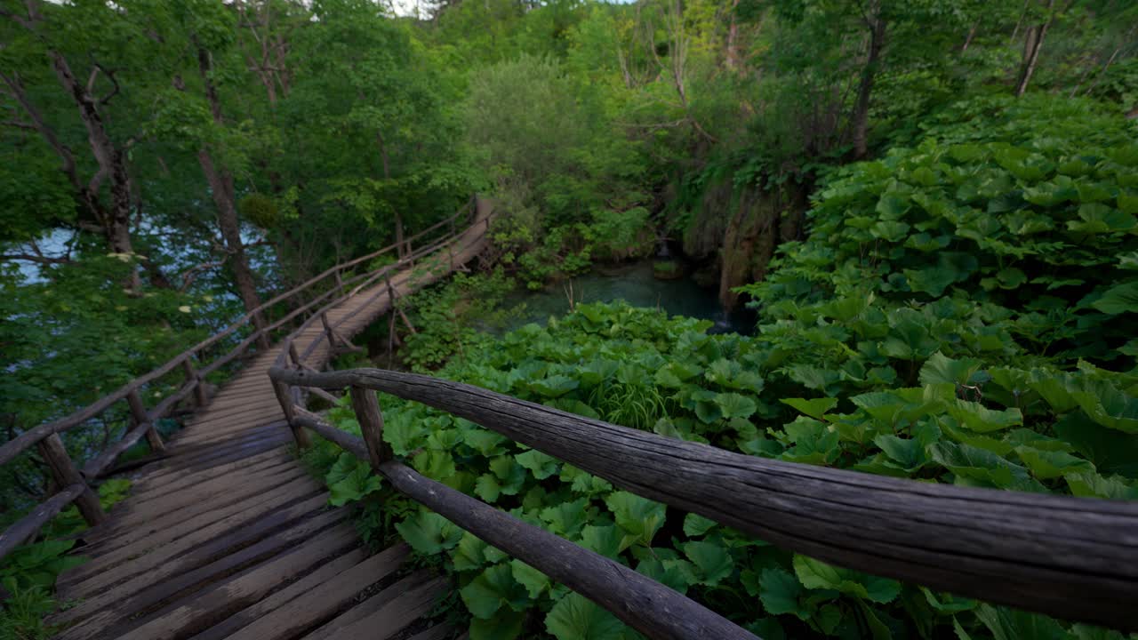 Plitvice Croatia waterfall. Surrounded by lush spring nature with wooden path and handrail