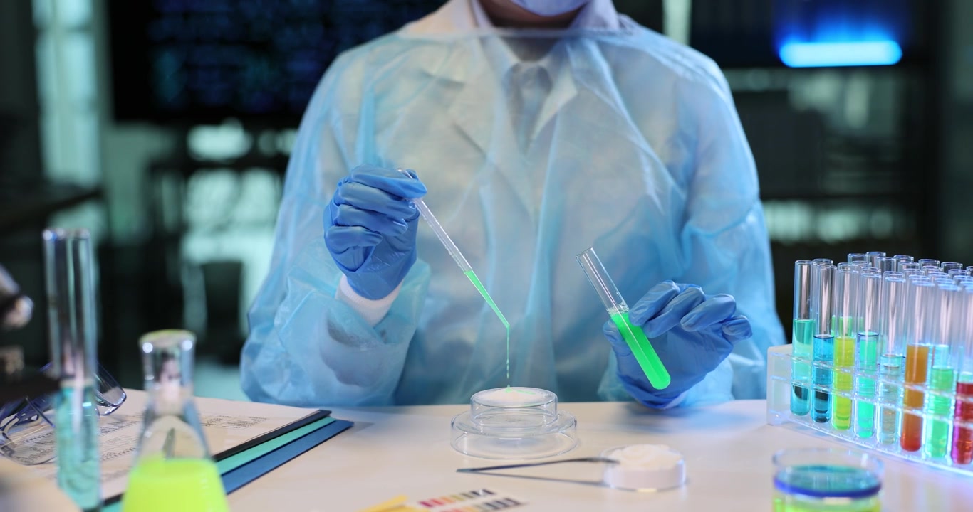 Researcher carefully pours green liquid onto microscope slide