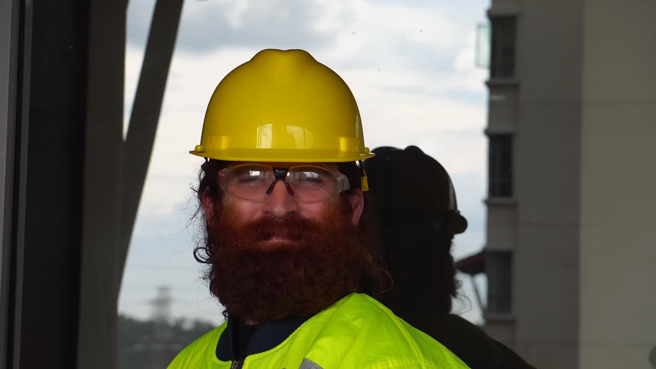 Portrait of a Construction Worker smoking out doors on break at job site in urban city setting with sky reflection as background