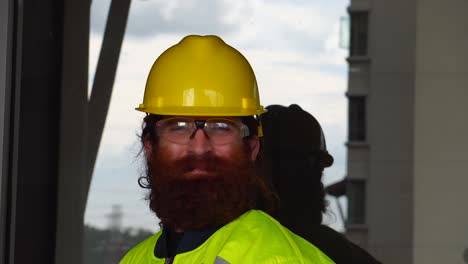 portrait of a construction worker smoking out doors on break at job site in urban city setting with sky reflection as background