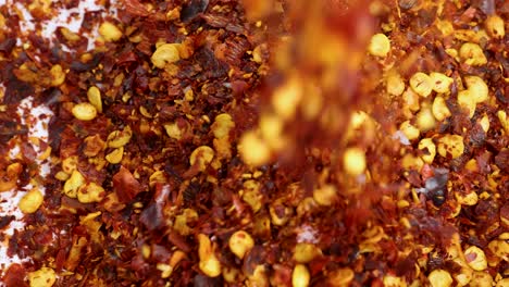 dried chili flakes cascade onto a white surface in a vibrant, close-up macro shot with dynamic motion