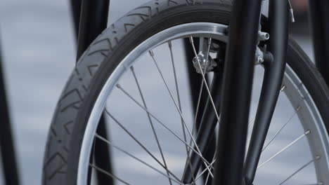 closeup front bicycle wheel standing on shared parking. alternative transport.