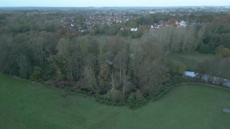 strafing and moving from the right to the left side of the frame, over some swampy areas, trees, narrow stream, and a village nearby in the county of norfolk, east side of london, united kingdom