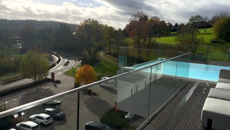 Toma-Panorámica-Que-Muestra-Un-Hotel-De-Lujo-Con-Piscina-Infinita-En-La-Azotea-Y-Estacionamiento-De-Autos-En-El-Lago-Sorpesee,-Alemania