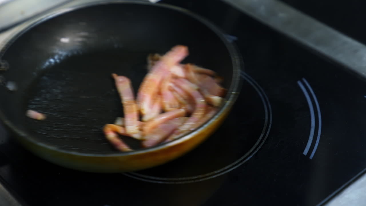 Chef cooking breakfast. Turning an amazing crispy bacon, rich in fat and colour. Sizzling and smoking in a hot pan.