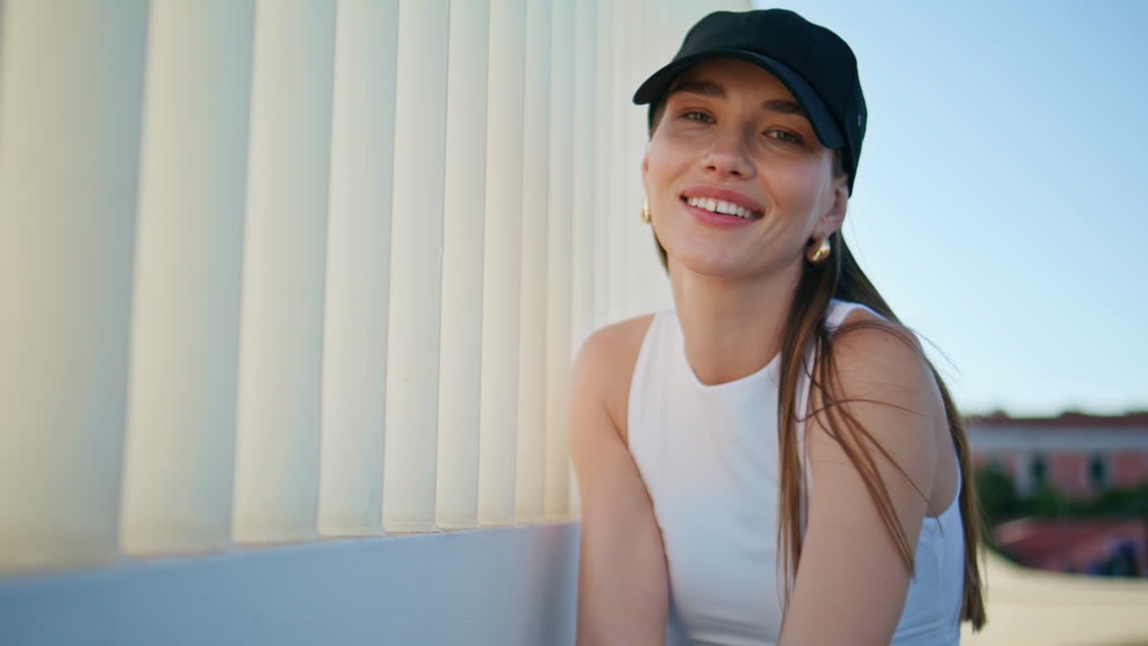 Portrait joyful woman posing at urban railings looking camera with playful smile