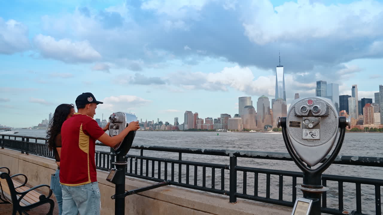 Jersey City, USA, 11 luglio 2025: turisti a un binocolo rivolti verso lo skyline di Manhattan. Due turisti a un binocolo sul lungomare di Jersey City con i grattacieli di Manhattan sullo sfondo.