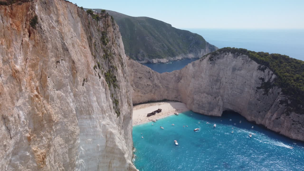 mujer caucásica con bandera griega en el acantilado de la playa de zakynthos