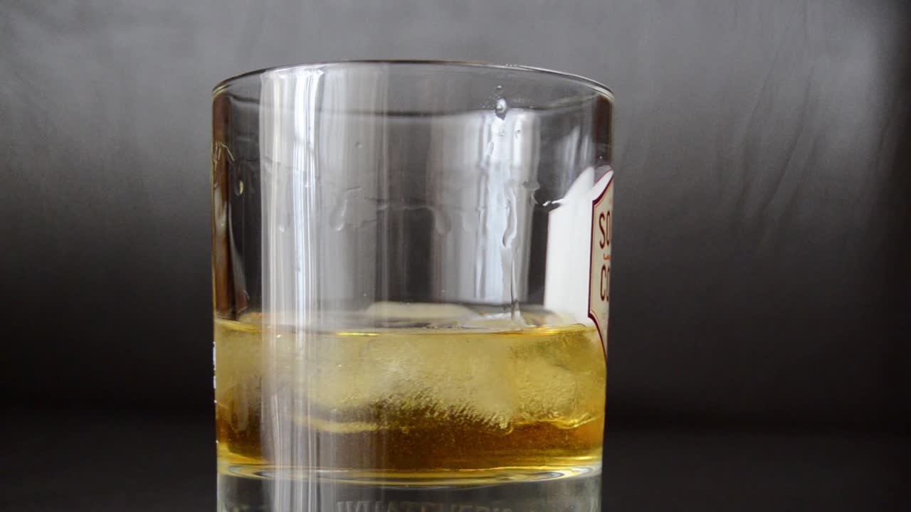 whisky girando en el vaso con cubitos de hielo