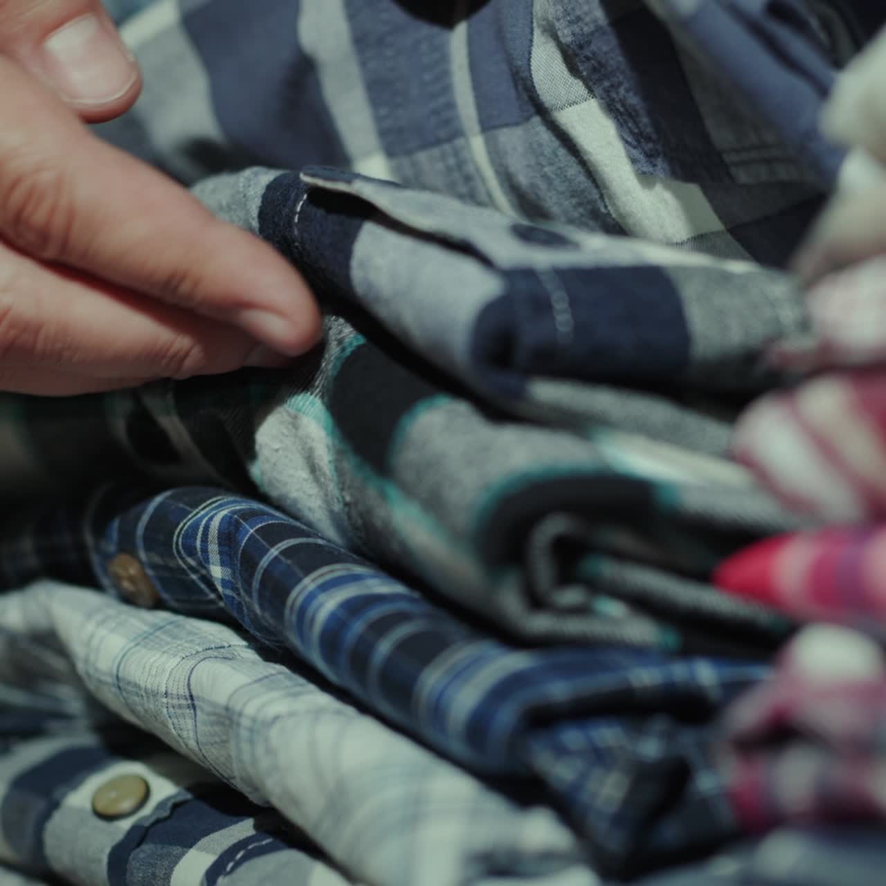 A man chooses a shirt from a neat pile