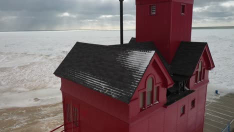 Holland,-Michigan-lighthouse-in-the-winter-at-Lake-Michigan-with-drone-moving-up-with-American-flag