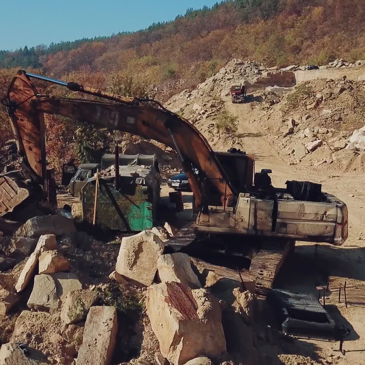 professional equipment are working in the quarry with stones on the background of a hill with a forest. View of the sand quarry. Camera motion straight
