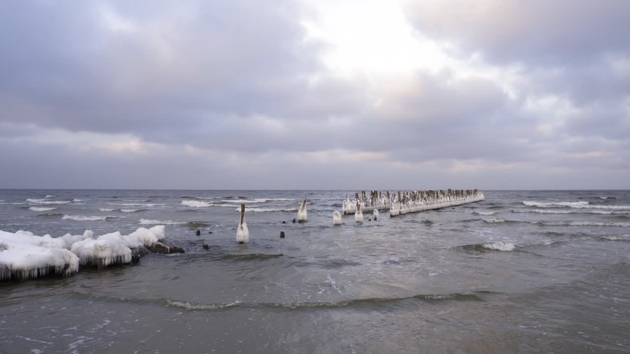 старый деревянный пирс в балтийском море, покрытый льдом зимой в пасмурный день