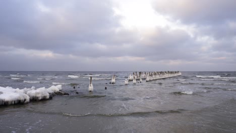antiguo muelle de madera en el mar báltico cubierto de hielo durante el invierno en un día nublado